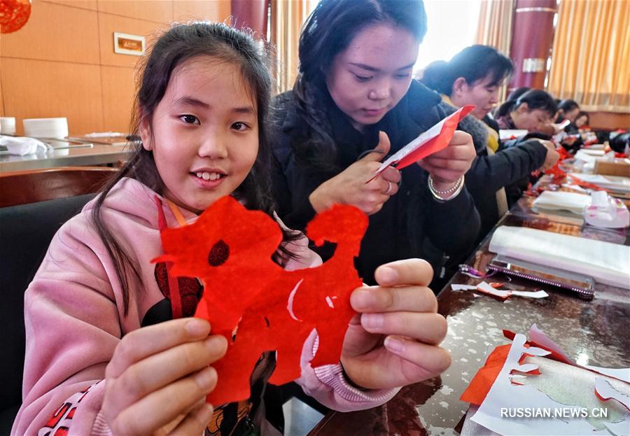Жители поселка Чансиньдянь учатся вырезать из бумаги и готовить новогодние блины