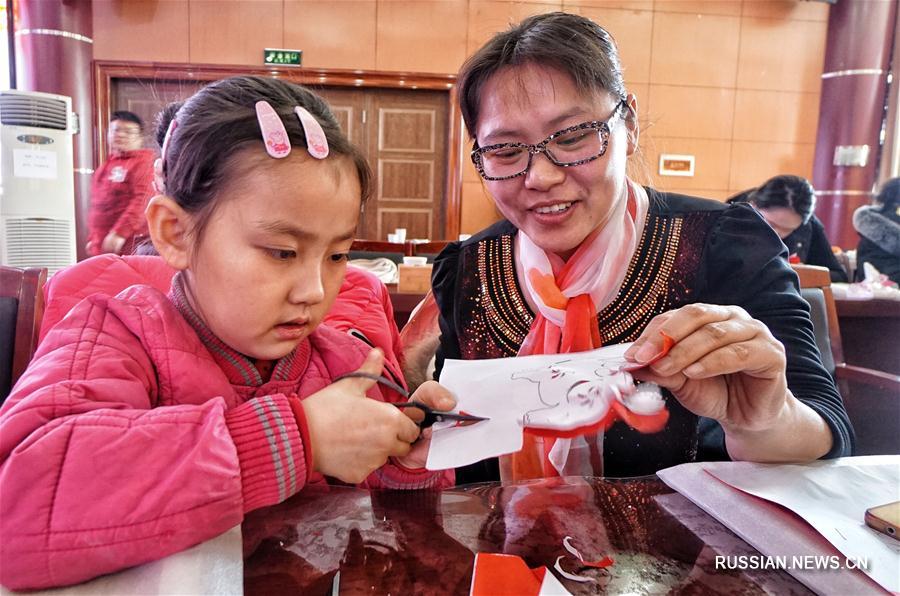 Жители поселка Чансиньдянь учатся вырезать из бумаги и готовить новогодние блины