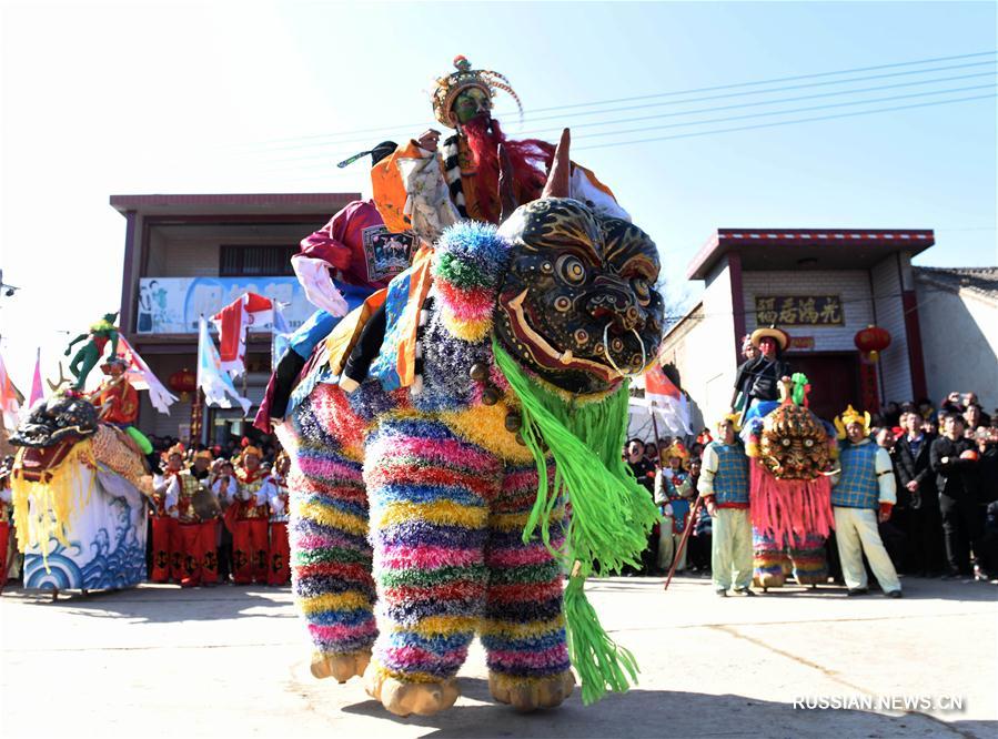 Праздничное шествие на ходулях в костюмах зверей в поселке Цинхэ 