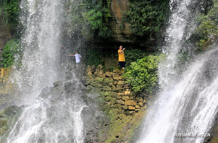 Туристы любуются водопадом, наслаждаясь прохладным воздухом на юге Китая