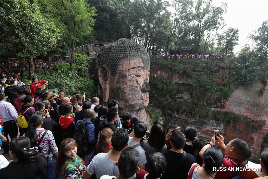 Туристы возле огромной статуи Будды в городском округе Лэшань провинции Сычуань