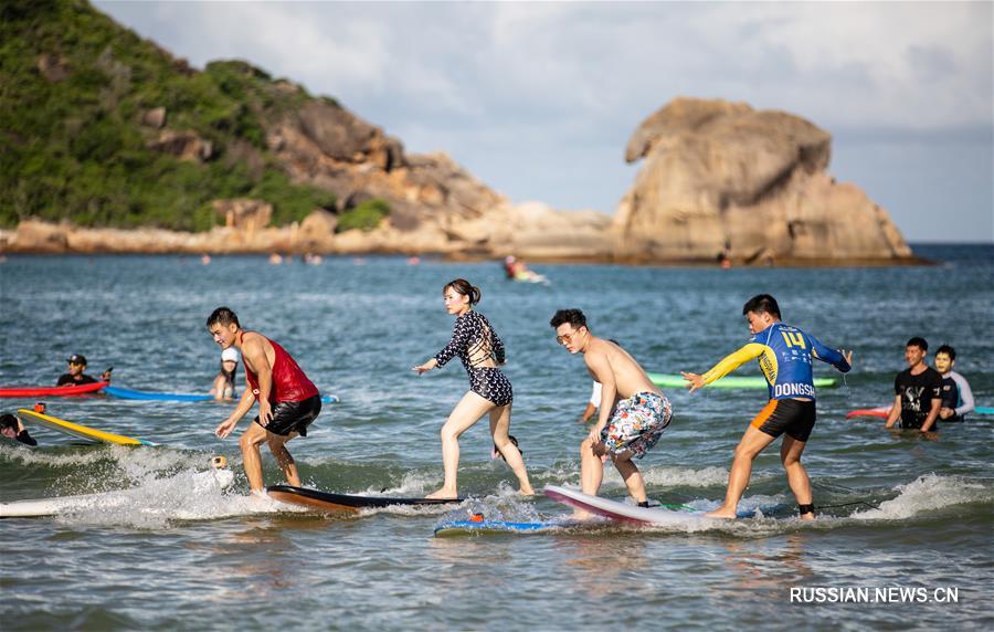 Наслаждение радостью от серфинга на море близ побережья китайского острова Хайнань