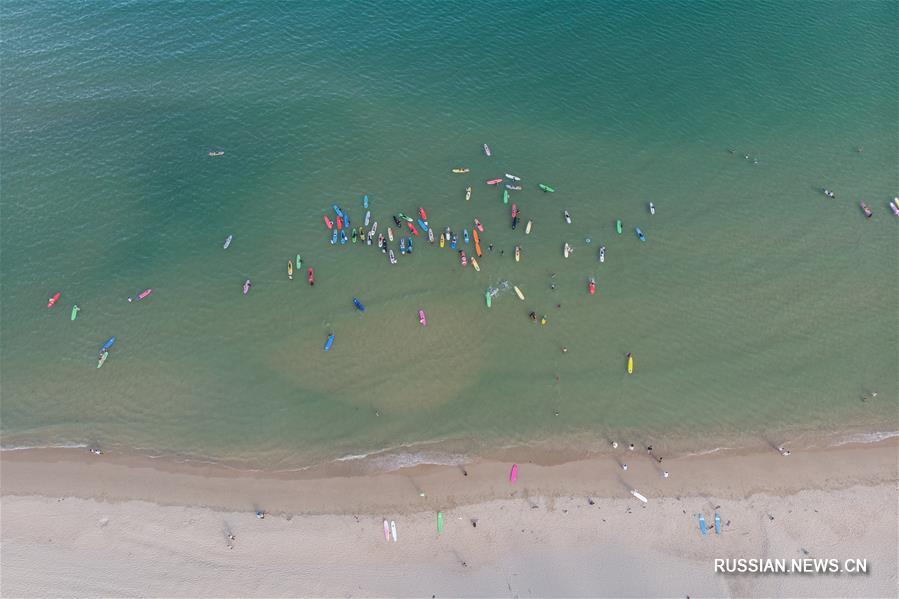 Наслаждение радостью от серфинга на море близ побережья китайского острова Хайнань