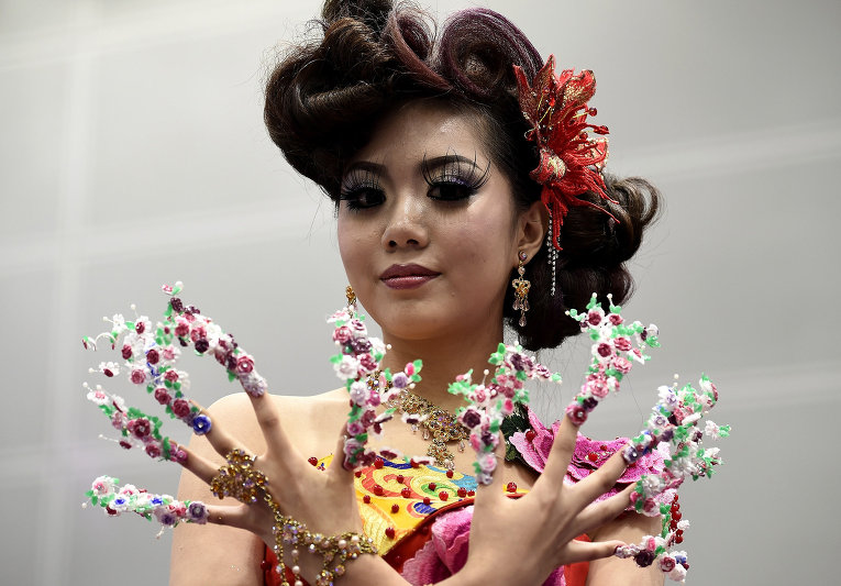 Модель представляет творение дизайнера во время конкурса парикмахерского искусства и искусства макияжа в Куала-Лумпуре