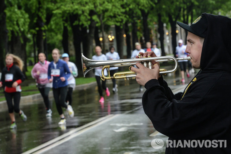 Музыкант играет на трубе во время благотворительного забега 