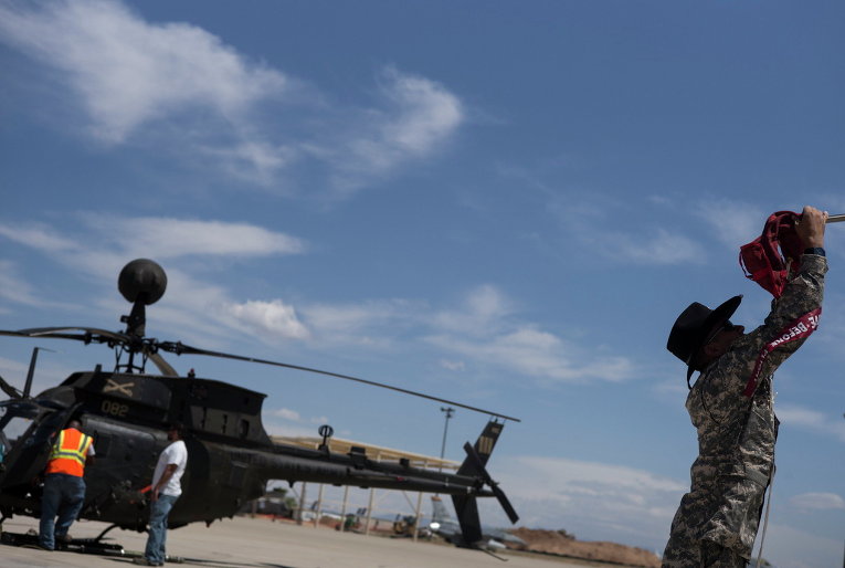 Военнослужащий зачехляет лопасти вертолета OH-58 Kiowa на авиабазе ВВС США 