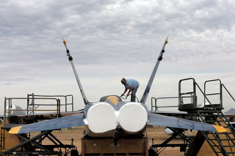 Военнослужащий покрывает водонепроницаемой краской американский истребитель-бомбардировщик F-18 на авиабазе ВВС США 