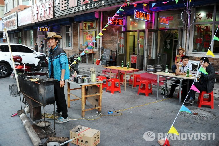 Мужчина готовит еду на мангале на одной из улиц Маньчжурии