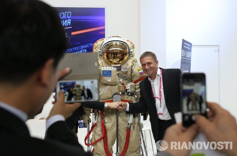 Посетитель фотографируется со скафандром на стенде Роскосмоса на Международной промышленной выставке 