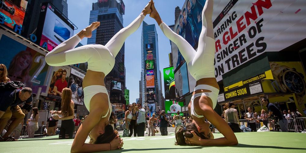 Тысячи любителей йоги отметили летнее солнцестояние бесплатным уроком на Таймс-сквер в Нью-Йорке